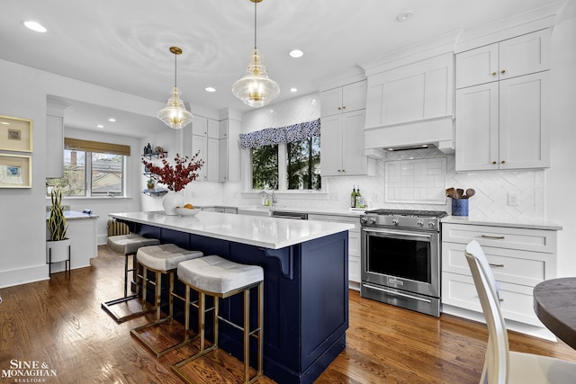 kitchen featuring light countertops, stainless steel appliances, recessed lighting, white cabinetry, and a kitchen bar