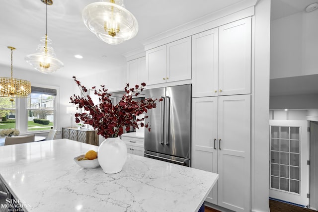kitchen with a kitchen island, white cabinetry, a chandelier, light stone counters, and high end refrigerator