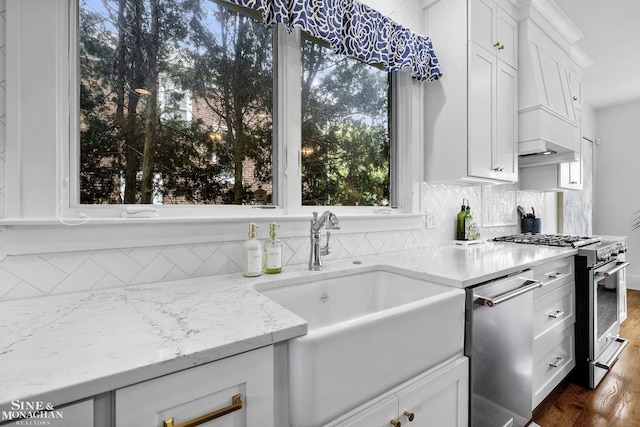 kitchen with light stone counters, appliances with stainless steel finishes, a sink, and tasteful backsplash