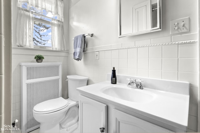 bathroom featuring vanity, toilet, and tile walls