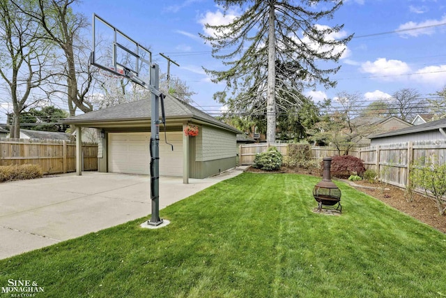 view of yard featuring a detached garage, fence, an outdoor structure, and an outdoor fire pit