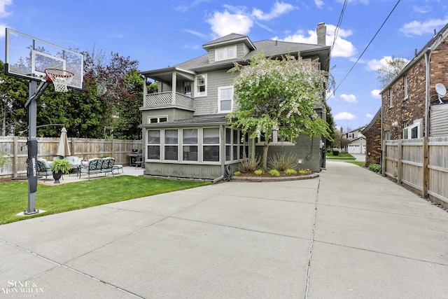 exterior space with fence, a sunroom, a chimney, a balcony, and a lawn