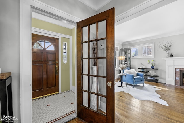 entrance foyer with plenty of natural light, ornamental molding, a fireplace, and wood finished floors