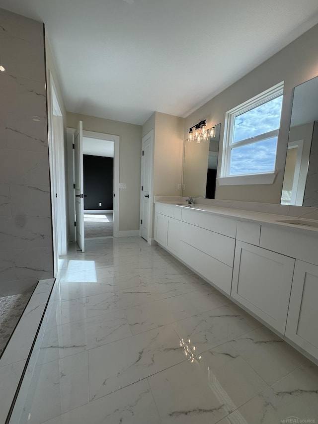full bathroom with baseboards, marble finish floor, double vanity, and a sink