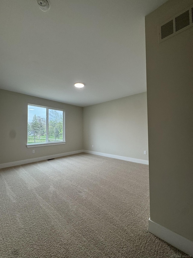 unfurnished room with carpet, visible vents, and baseboards