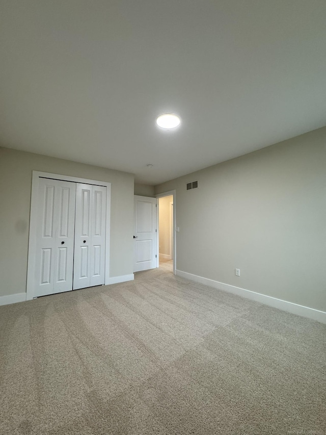 unfurnished bedroom featuring baseboards, a closet, visible vents, and carpet