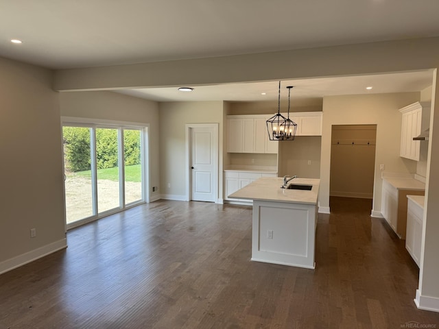 kitchen featuring baseboards, white cabinets, recessed lighting, and a sink