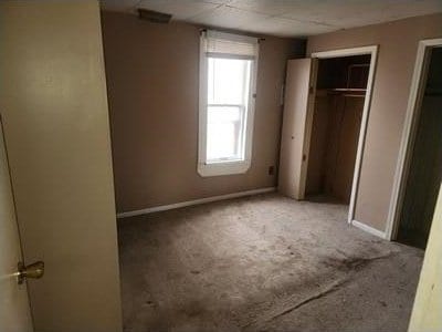 unfurnished bedroom featuring baseboards, carpet flooring, and a closet