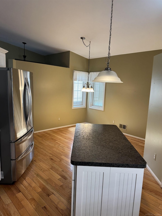 kitchen with visible vents, dark countertops, light wood-style flooring, freestanding refrigerator, and white cabinetry