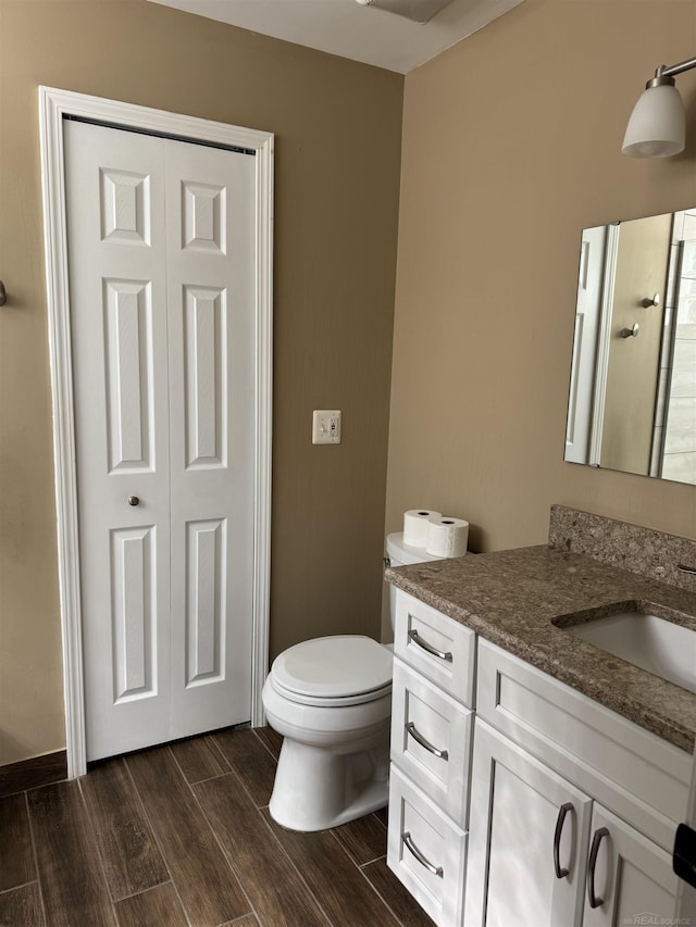 bathroom featuring toilet, wood finished floors, and vanity
