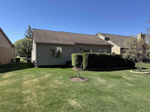 rear view of property with a lawn, a chimney, and cooling unit
