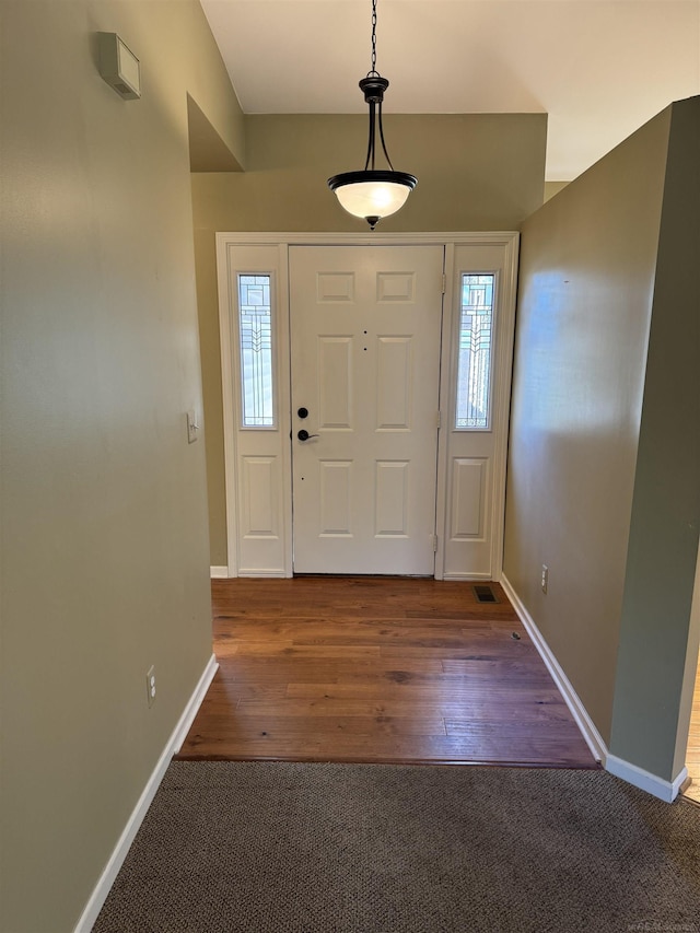 carpeted entrance foyer featuring baseboards, visible vents, and wood finished floors
