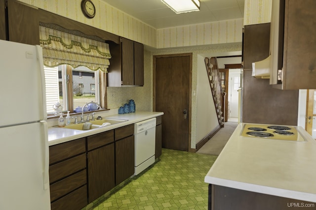 kitchen featuring dark brown cabinets, white appliances, light floors, light countertops, and a sink