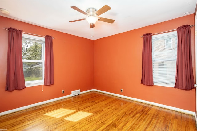 spare room featuring baseboards, ceiling fan, light wood finished floors, and visible vents