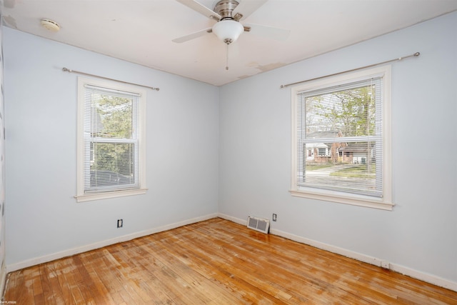 spare room featuring baseboards, visible vents, ceiling fan, and light wood finished floors