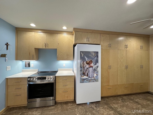 kitchen with light countertops, stainless steel electric range oven, light brown cabinets, and freestanding refrigerator