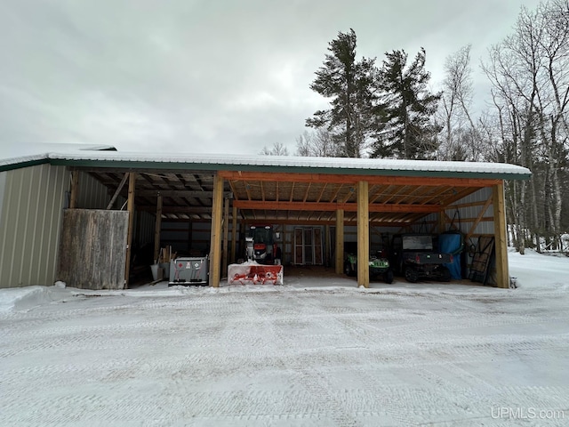 snow covered parking area with a pole building and a detached carport