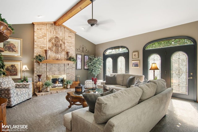 living area featuring beamed ceiling, ceiling fan, carpet, and a fireplace