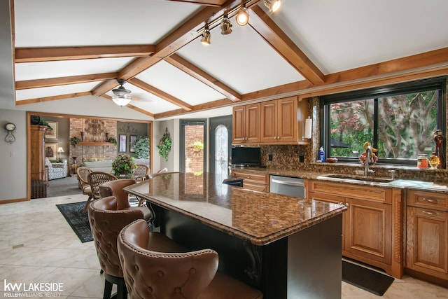 kitchen with vaulted ceiling with beams, plenty of natural light, a sink, and dishwasher