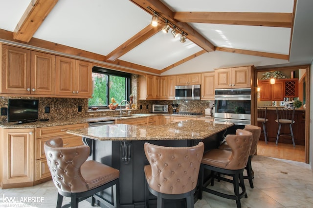 kitchen featuring decorative backsplash, light stone countertops, a center island, a sink, and appliances with stainless steel finishes