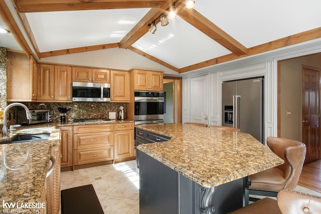 kitchen with a sink, appliances with stainless steel finishes, backsplash, and light stone countertops