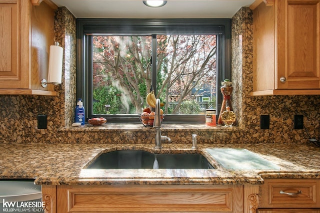 kitchen with stone countertops, a sink, and decorative backsplash