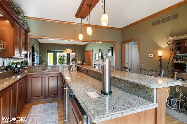 kitchen featuring light wood-style floors, light stone counters, ornamental molding, and visible vents