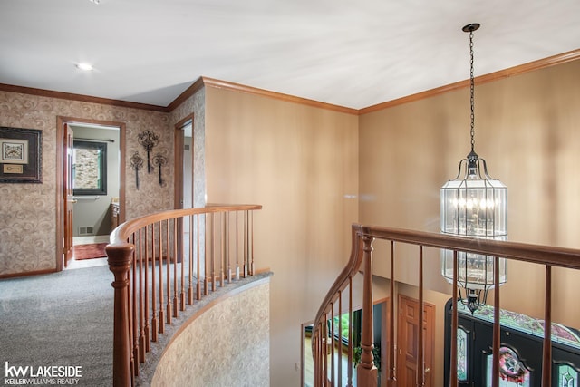 hallway with crown molding, carpet flooring, a notable chandelier, wallpapered walls, and an upstairs landing