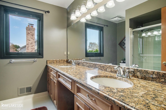 bathroom with baseboards, visible vents, a shower stall, and a sink