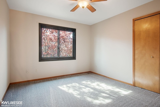 empty room with carpet flooring, ceiling fan, and baseboards