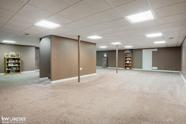 finished basement featuring baseboards, carpet flooring, and a drop ceiling