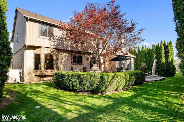 back of house featuring a yard and brick siding