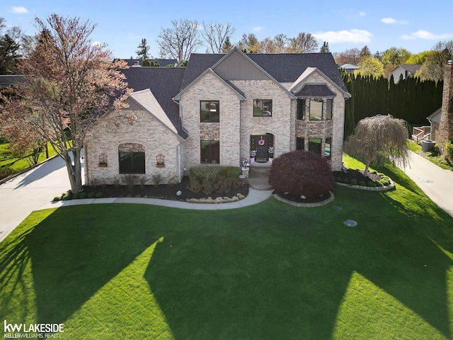 french country home with concrete driveway, a front yard, and stone siding