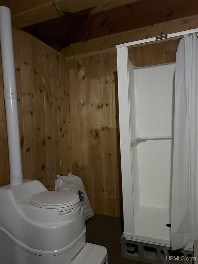 full bathroom with wooden walls, toilet, and a shower with curtain