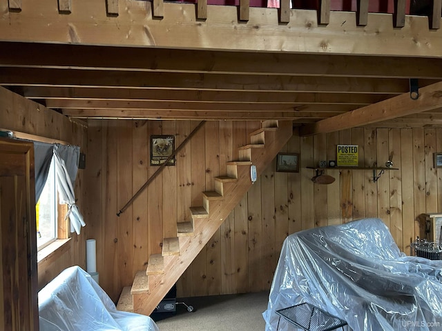 interior space with wood walls, stairs, and carpet flooring