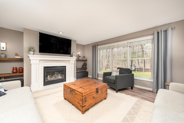 living area with a brick fireplace, baseboards, and wood finished floors
