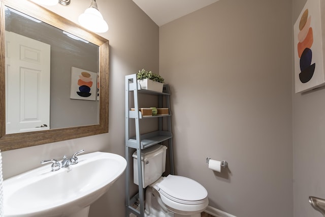 bathroom featuring toilet, baseboards, and a sink