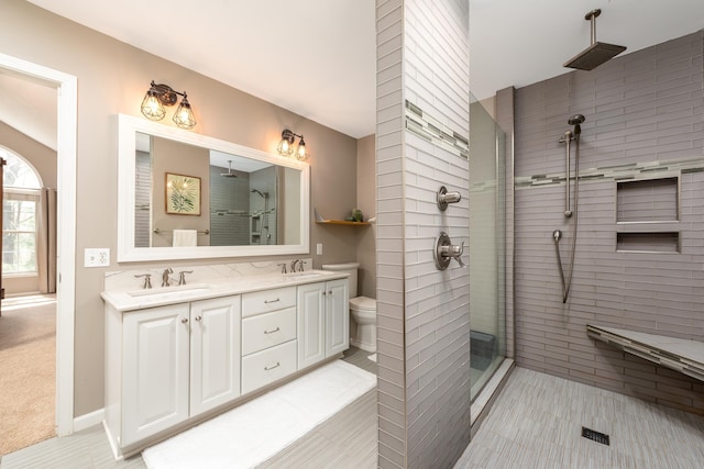 full bathroom featuring a sink, a tile shower, and double vanity
