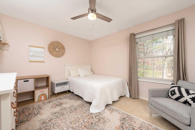 carpeted bedroom featuring baseboards, a ceiling fan, and multiple windows