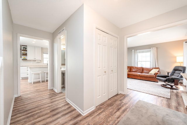 corridor with baseboards and light wood-style flooring