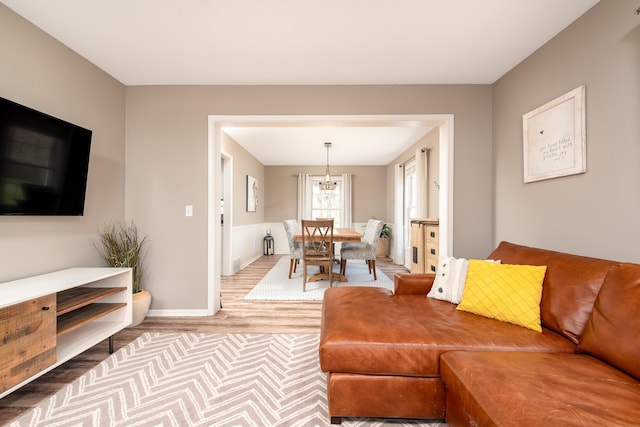 living room with baseboards, wood finished floors, and an inviting chandelier