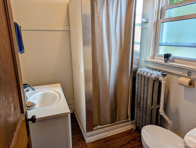 bathroom featuring vanity, radiator, wood finished floors, toilet, and a shower with curtain