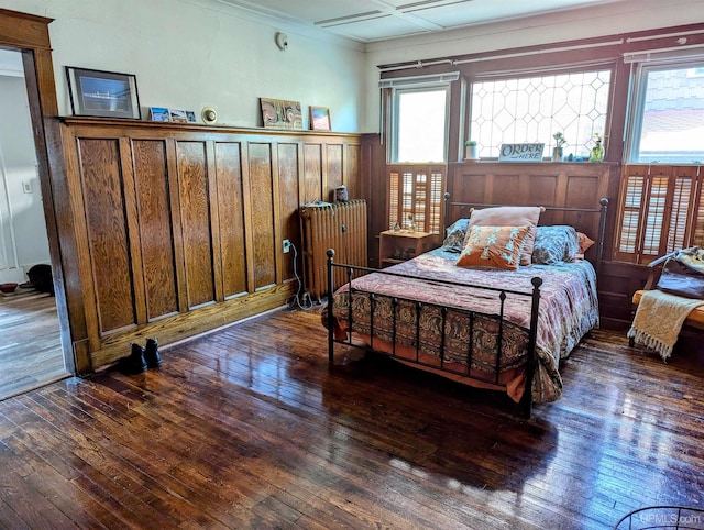 bedroom featuring wood-type flooring, ornamental molding, and wainscoting
