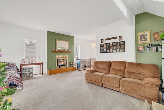 carpeted living room with a glass covered fireplace, vaulted ceiling, and a notable chandelier