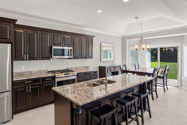 kitchen featuring a sink, light tile patterned floors, an inviting chandelier, a breakfast bar, and stainless steel appliances
