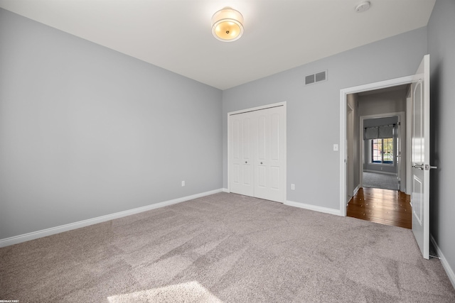 unfurnished bedroom featuring baseboards, carpet, a closet, and visible vents