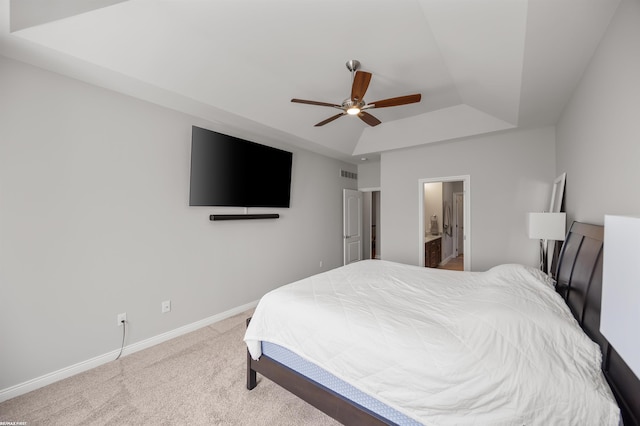 carpeted bedroom featuring visible vents, baseboards, connected bathroom, a tray ceiling, and a ceiling fan