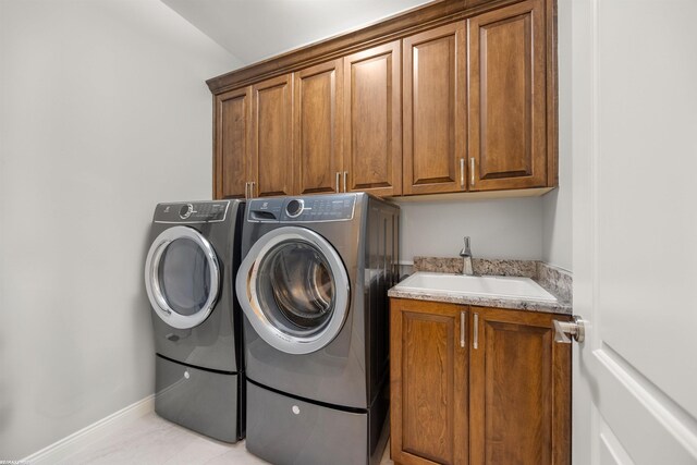 laundry room with cabinet space, washing machine and dryer, and a sink