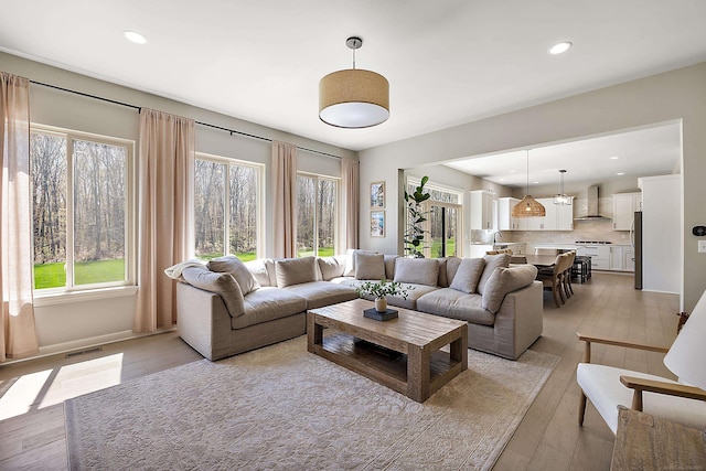 living area with recessed lighting, baseboards, visible vents, and light wood-style floors