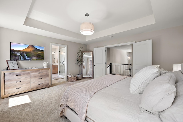 bedroom with light carpet, a tray ceiling, and connected bathroom